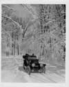 1912 Packard phaeton, on winter road, with male driver and two passengers, front view