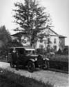 1921-1922 Packard touring car with female driver next to large house