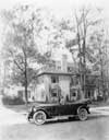 1920-1923 Packard touring car in front of large home, Alvan Macauley in driver