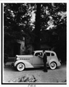 1937 Packard sedan, female driver, parked in front of home, male standing at driver