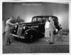 1937 Packard touring sedan, salesman speaking to couple at front side