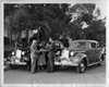1938 Packard touring sedans parked on street, couple and salesman in between cars