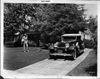 1932 Packard convertible victoria and owner Dick Powell standing on lawn near driveway