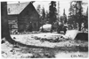 Rapid motor truck passing log cabin on mountain road in Colorado, at 1909 Glidden Tour