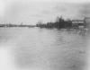 Flooded river with homes and Standpipe in background, Lansing, 1904
