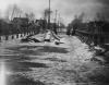 Three women on bridge in flooded area, Lansing, 1904
