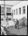 Two people digging in lawn planting a flag pole