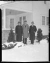 Three men in winter clothes posing in front of house