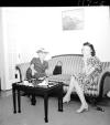 Two women seated on formal couch, one smoking