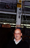 Dick Budd demonstrates the correct use of earplugs as the sign mounted at the top of the pillar behind him shows.